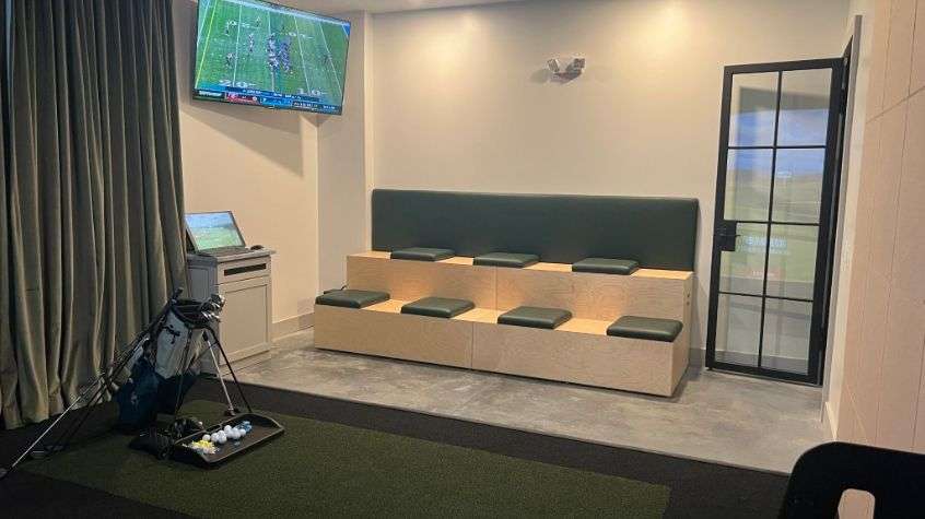 Tiered seating and golf simulator area inside RPI’s new facility